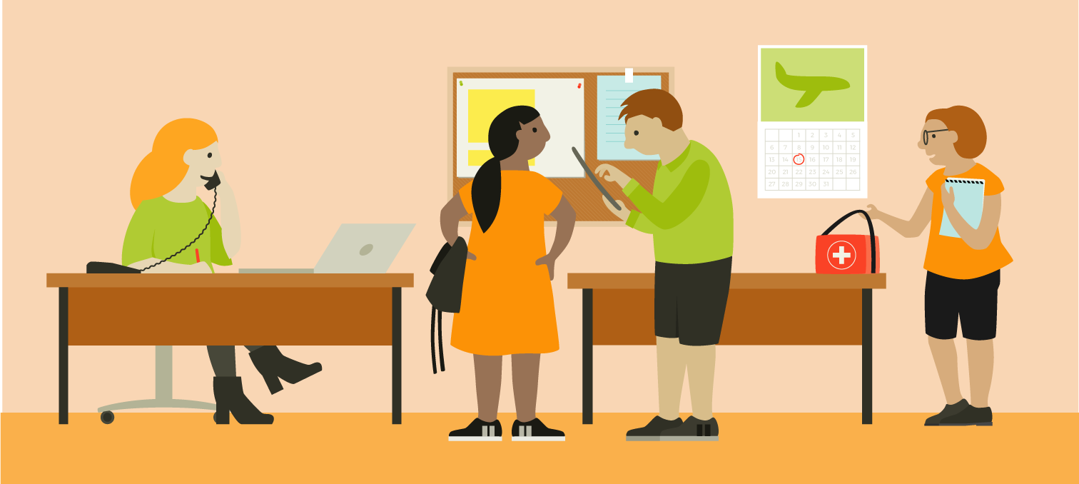 A group of people indoors, a woman is on the phone behind a desk, two people are standing talking to eachother in front of an information board and a woman has placed a first aid bag on top of a table.